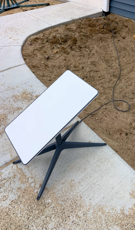 A Starlink dish, which is shaped like a square, sits on a walkway to a home