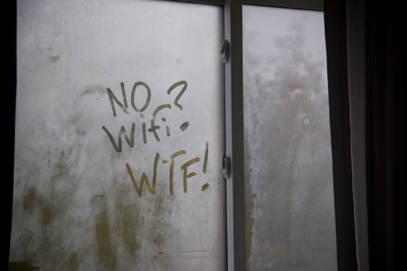 A fogged window has a message written by someone's finger: "No WiFi? WTF!"