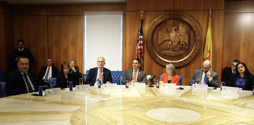 Screenshot of NM Governor and lawmakers seated around table during bill signing press conference