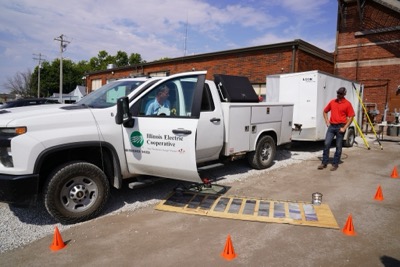 An Illinois Electric Cooperative truck with its driver side door open while a cooperative employee walks to greet driver