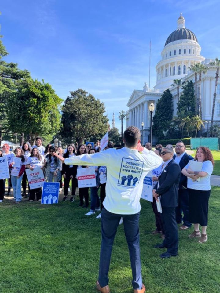 Several dozen digital equity advocates hold a rally on the lawn of the California statehouse