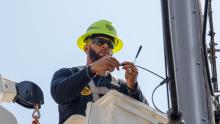 Fiber technician connecting a wire while elevated in a bucket truck