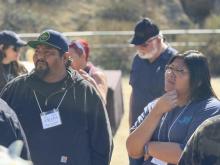 William wearing a baseball cap with JNET insignia on cap stands next to JNET operations manager Angela listening intently to TBB instructor